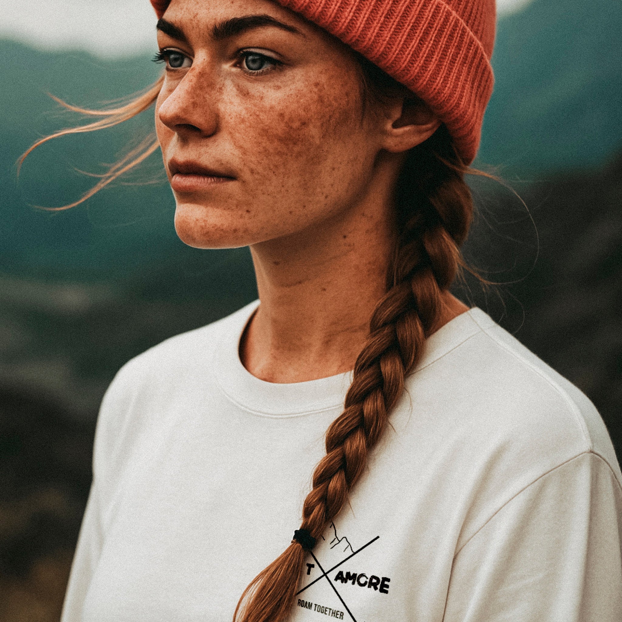 Frau mit gepflochtenem Haar und Sommersprossen trägt unser Bio-Baumwoll Longsleeve mit Pfotenprint.
